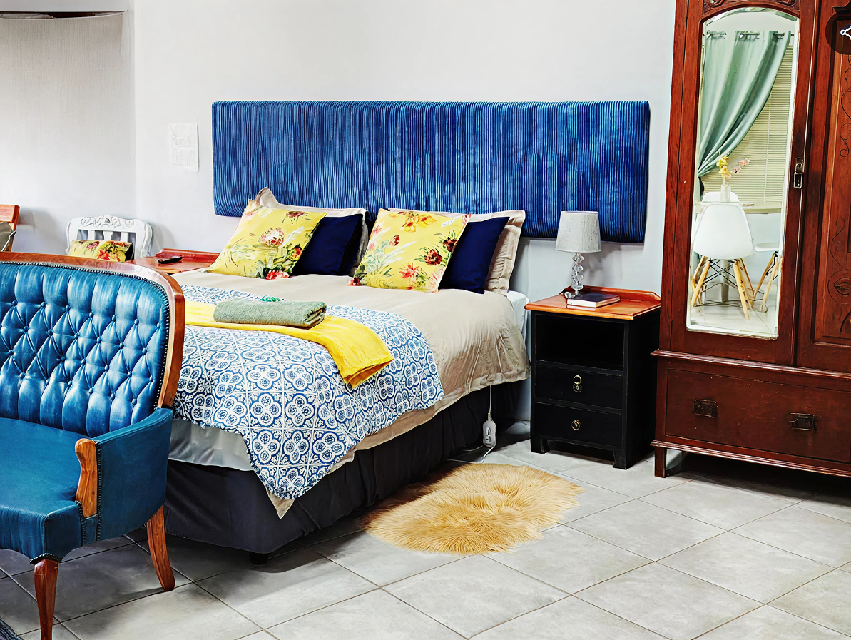 Bedroom with blue headboard and tufted chair