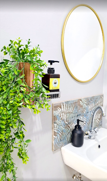 Bathroom basin with gold mirror and greenery